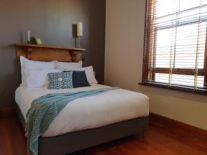 a bedroom with a bed with a blue blanket on it at Salty Eyre Glenelg in Glenelg