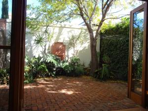 an open door to a garden with a tree at Salty Eyre Glenelg in Glenelg