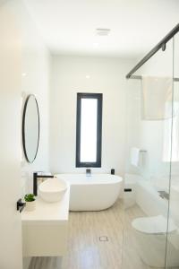a white bathroom with a tub and a sink at Myrtle Tree Lodge - Trunks in Kangaroo Valley