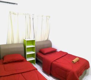 a bedroom with two beds with red sheets and a shelf at Izzanial Homestay in Sandakan