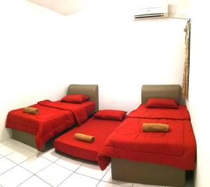 two beds in a room with red sheets and pillows at Izzanial Homestay in Sandakan