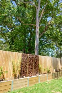 a wooden fence with a tree behind it at Myrtle Tree Lodge - Trunks in Kangaroo Valley