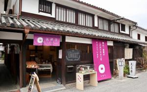 un negozio di fronte a un edificio con uno striscione rosa di Temari Inn Yukikai a Kurashiki