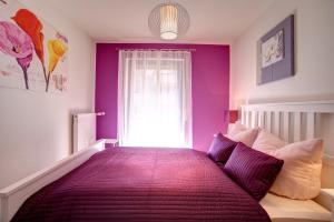 um quarto com uma cama com paredes roxas e uma janela em Ferienwohnung Seeblick em Schalkenmehren