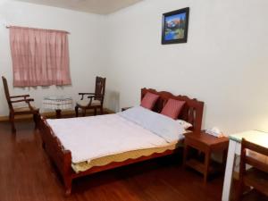 1 dormitorio con 1 cama y 2 sillas en Minine Guesthouse, en Silang