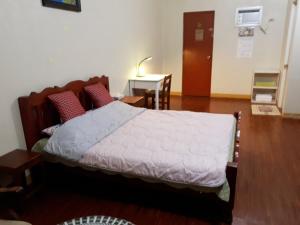 ein Schlafzimmer mit einem Bett und einem Tisch in einem Zimmer in der Unterkunft Minine Guesthouse in Silang