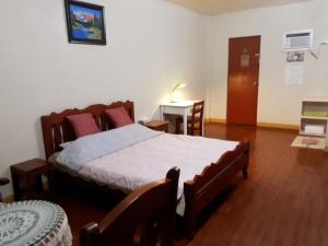 1 dormitorio con cama, mesa y escritorio en Minine Guesthouse, en Silang