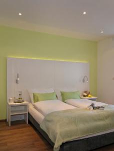 a bedroom with a large bed with green walls at Schlotzeria Hotel I Café I Eis in Grenzach-Wyhlen +2 photos
