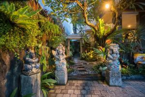 ogród z posągami w środku ścieżki w obiekcie Griya Tunjung Sari w mieście Denpasar