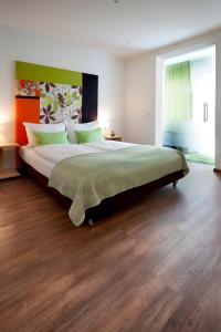 ein großes Schlafzimmer mit einem großen Bett mit grüner Bettwäsche in der Unterkunft Schlotzeria Hotel I Café I Eis in Grenzach-Wyhlen