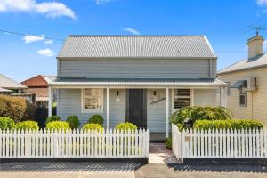 a white fence in front of a house at Geelong West Miner's Cottage in Geelong