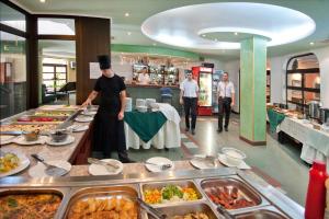 a chef preparing food in a buffet line in a restaurant at Hotel Sigma in Kiten