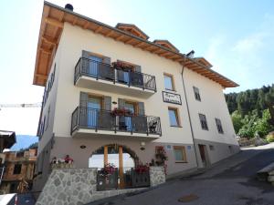 un edificio con balcones y flores. en Aparthotel Dolomites Living&Relax en Commezzadura