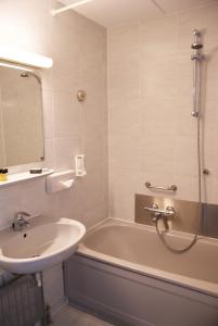 ein Badezimmer mit einem Waschbecken und einer Badewanne mit einem Spiegel in der Unterkunft Fletcher Hotel - Restaurant Nieuwvliet Bad in Nieuwvliet-Bad