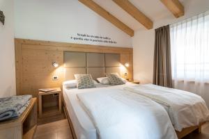 a bedroom with a large white bed and a window at Aparthotel Dolomites Living&Relax in Commezzadura