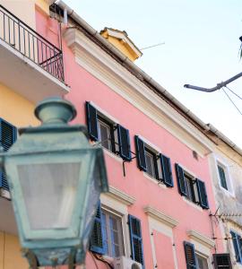 un edificio rosa con un lampione davanti di Kampielo Apartment a Città di Corfù