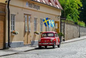un pequeño coche rojo estacionado frente a un edificio en Hotell Stenugnen en Visby