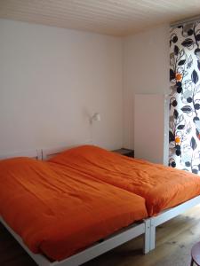 a bedroom with a bed with an orange blanket at Les Mouresses in Savièse
