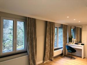 Zimmer mit Fenstern, einem Schreibtisch und einem Stuhl in der Unterkunft Reichel-Appartements in Baden-Baden