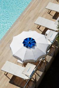 un gruppo di tavoli e ombrelloni accanto alla piscina di Miriam Hotel & Residence a Pietra Ligure