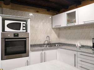 a kitchen with a microwave and a sink at Casa Carlán in Melide