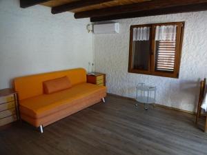 - un canapé orange dans une chambre avec fenêtre dans l'établissement Holiday appartment, à Žuljana