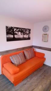 an orange couch in a room with a clock on the wall at Ferienwohnung Witzig Inh Rita Weitmann in Ingelheim am Rhein