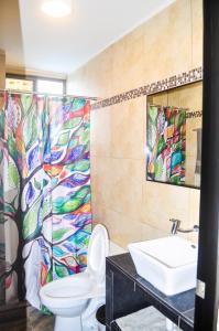 a bathroom with a toilet and a sink with a colorful shower curtain at Blue Ocean Apartments Chipipe in Salinas