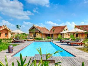 a resort pool with benches and umbrellas at Emeralda Resort Ninh Binh in Ninh Binh