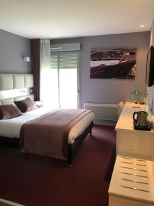 a bedroom with a bed and a tv and a window at Hôtel du Golf Saint Lazare in Limoges