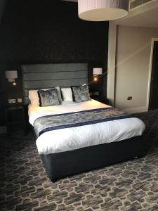 een slaapkamer met een groot bed met witte lakens en kussens bij The Troll Cart Wetherspoon in Great Yarmouth