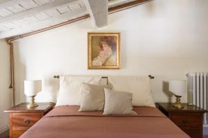 a bedroom with a bed with two lamps and a painting at Casa Ribes - Fattoria la Speranza, Case Toscane in Anghiari