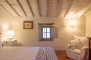 um quarto com uma cama, uma cadeira e uma janela em Fattoria la Speranza, Case Toscane, Casa Vaniglia em Anghiari
