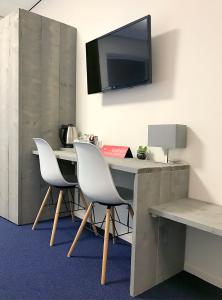 a desk with two chairs and a television on a wall at Belgische Loodsensociëteit in Vlissingen