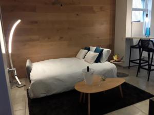 una camera con un letto bianco e una parete in legno di Hébergement Les Heros a Liegi