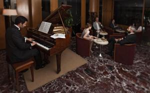 un grupo de personas sentadas alrededor de un piano en Hotel Best, en Ankara