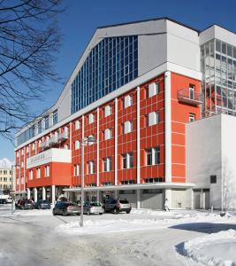 un gran edificio rojo con coches estacionados en un estacionamiento en Hotel Spolcentrum en Svit