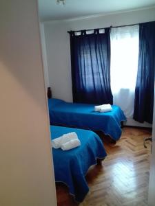 2 camas en una habitación con sábanas azules y ventana en Colon Apartment en Mendoza