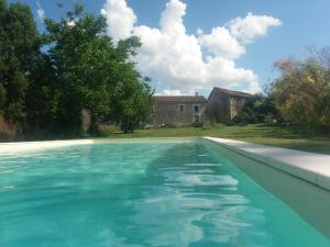 a pool of blue water with a house in the background at Le Petit Bouchon in Parcoul +14 photos