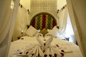 Dos cisnes hechos de toallas en una cama en Riad Anabel, en Marrakech