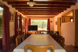 a dining room with a table and chairs and a television at Ventana a los Cerros in Villa La Angostura