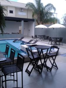 a group of tables and chairs next to a swimming pool at Revitalle Hotel in Votuporanga