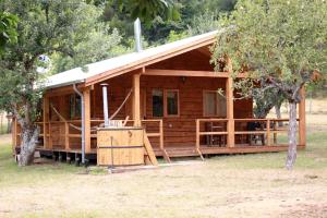 uma cabana de madeira com um alpendre e uma árvore em Karkú Lodge em Pucón