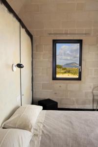 a bedroom with a bed and a window at Cala Rossa Lodge in Favignana