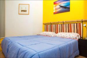 ein Schlafzimmer mit einem blauen Bett und einer gelben Wand in der Unterkunft Los Cristianos Tenerife in Los Cristianos