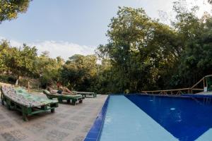 una piscina con dos personas sentadas en bancos junto a ella en Entre Bosques Tayrona, en Los Naranjos