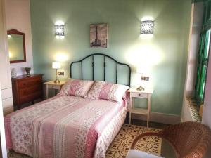 a bedroom with a bed with a pink blanket and two tables at Hostal El Faro in Chipiona