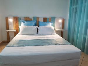 1 cama grande con sábanas blancas y almohadas azules en GÏTE REVE CARAIBES " LA PERLE ", en Bouillante