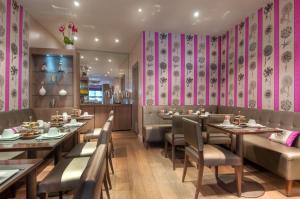 een restaurant met tafels en stoelen en roze muren bij Hotel Massena in Parijs