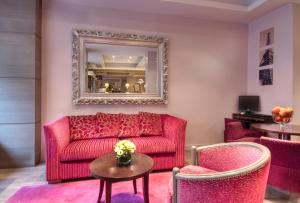 a living room with a red couch and two chairs at Hotel Massena in Paris